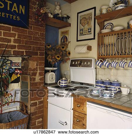 Stock Photo - Old-fashioned white electric oven in corner of cottage kitchen with blue+white Cornishware on plate rack. Fotosearch
