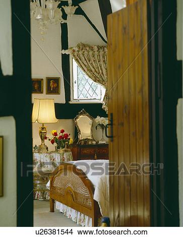 Picture - Old wooden cottage door open to bedroom with beamed walls and lighted lamp. Fotosearch