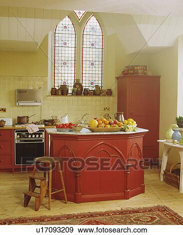 Stock Photo - Old wooden steps beside red island unit in traditional kitchen in reclaimed church with stained glass window&#13; &#10; &#13; &#10; &#13; &#10; &#13; &#10;. Fotosearch