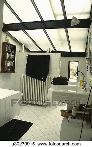 Opaque Glass Ceiling Panels In Modern White Bathroom With Black Towels And White Tiled Floor Stock Photography