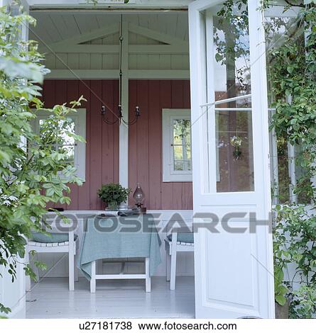 Stock Photo - Open door on table and chairs in traditional summerhouse. Fotosearch