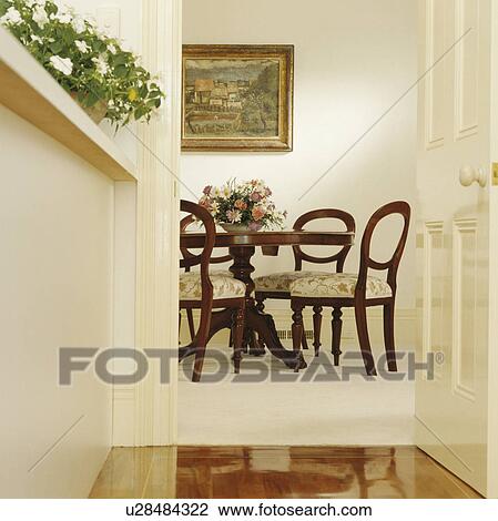 Stock Image - Open door with view of balloon-back Victorian chairs in white dining room. Fotosearch