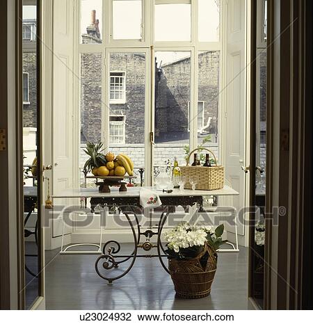 Open double doors to white hydrangea in pot on floor of dining room with marble topped metal table in front of window View Large Photo Image Stock Image - Open double doors to white hydrangea in pot on floor of dining room with marble topped metal table in front of window. Fotosearch