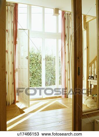 Stock Image - Open glass doors in barn conversion hall with wooden flooring. Fotosearch