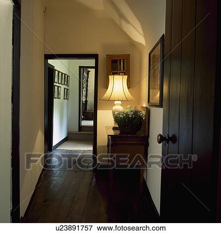 Open wooden door to lighted lamp on table in narrow cottage hall with dark wood floorboards View Large Photo Image Stock Photo - Open wooden door to lighted lamp on table in narrow cottage hall with dark wood floorboards . Fotosearch