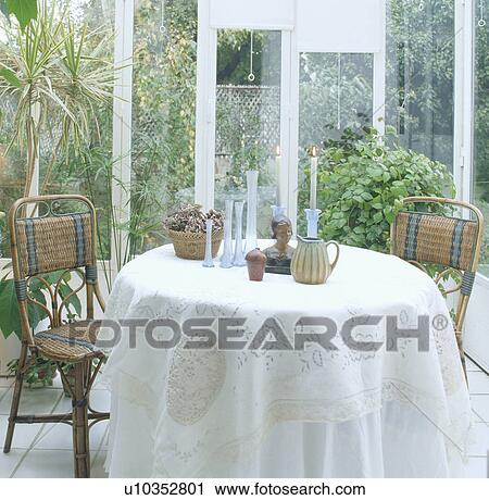 ornaments on table with white lace cloth in conservatory dining room with cane chairs and view of garden View Large Photo Image Stock Image - ornaments on table with white lace cloth in conservatory dining room with cane chairs and view of garden. Fotosearch