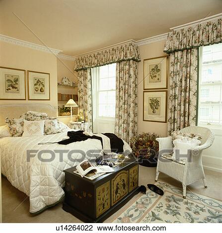 Painted antique chest and white Lloyd Loom armchair in bedroom with floral curtains and rug View Large Photo Image Stock Image - Painted antique chest and white Lloyd Loom armchair in bedroom with floral curtains and rug. Fotosearch