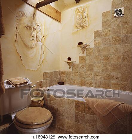Stock Image Of Painted Classical Head On Wall In Bathroom With Painted Classical Head On Wall In Bathroom With Travertine Tiles Bath Panel And