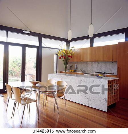 Pale Wood And Metal Chairs In Modern White Dining Room With Marble Topped Rectangular Island Unit And Wooden Flooring Stock Photography U14425915 Fotosearch
