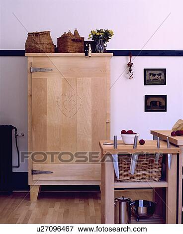Pale wood Shaker-style cupboard in white kitchen with knives stored on small wood table View Large Photo Image Stock Photo - Pale wood Shaker-style cupboard in white kitchen with knives stored on small wood table. Fotosearch