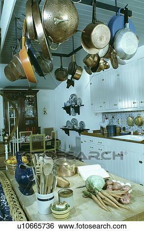Stock Photograph - Pans on metal rack above worktop with food preparation. Fotosearch
