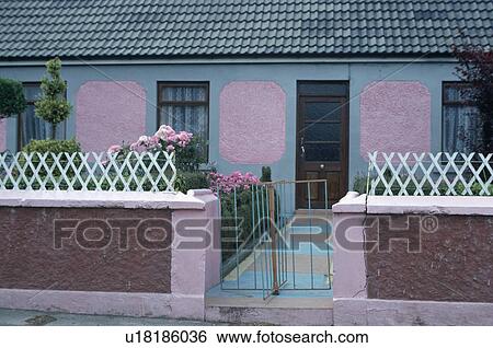 Stock Photograph - Pastel blue and pink single storey terraced cottage with trellis fence on garden wall. Fotosearch