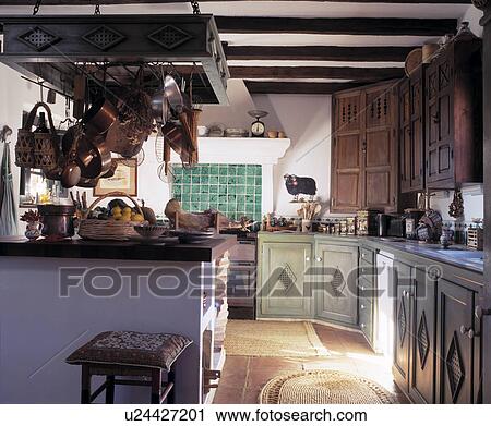Stock Image - Pastel green fitted cupboards below carved wooden fitted cupboards in traditional Spanish kitchen. Fotosearch