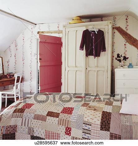 Patchwork quilt on bed in cottage bedroom with cream wardrobe and pink door View Large Photo Image Stock Photo - Patchwork quilt on bed in cottage bedroom with cream wardrobe and pink door. Fotosearch