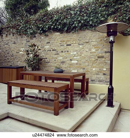 Patio heater and hard wood table and benches on raised paved patio in small walled city garden View Large Photo Image Picture - Patio heater and hard wood table and benches on raised paved patio in small walled city garden. Fotosearch
