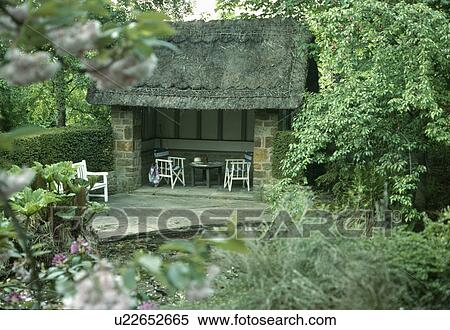 Patio in front of open thatched summerhouse with directors chairs in country garden View Large Photo Image Stock Photography - Patio in front of open thatched summerhouse with directors chairs in country garden. Fotosearch