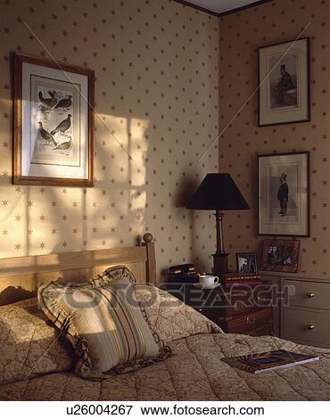 Patterned beige quilt and cushion in traditional bedroom with star-patterned wallpaper View Large Photo Image Stock Photo - Patterned beige quilt and cushion in traditional bedroom with star-patterned wallpaper. Fotosearch