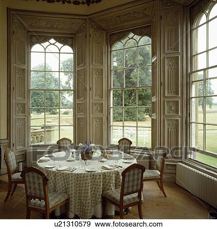 Patterned cloth on circular table in large dining room with tall Gothic windows and view of outdoors View Large Photo Image Stock Photo - Patterned cloth on circular table in large dining room with tall Gothic windows and view of outdoors. Fotosearch
