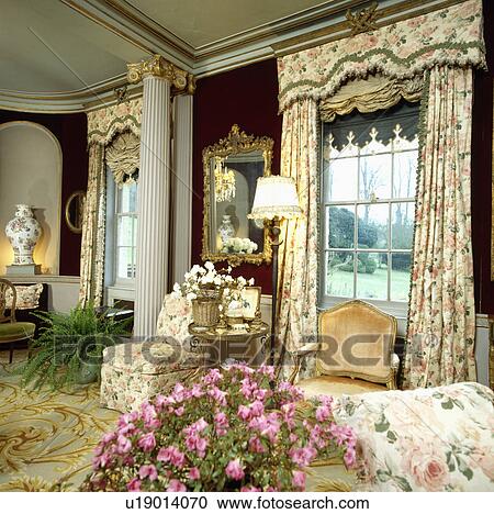 Stock Image - Patterned curtains in country drawing room with classical pillars. Fotosearch