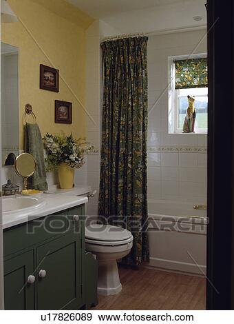 Patterned green curtain beside bath in pastel yellow bathroom with fitted green vanity unit View Large Photo Image Stock Photo - Patterned green curtain beside bath in pastel yellow bathroom with fitted green vanity unit. Fotosearch