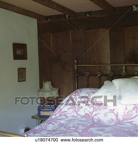 patterned pink linen on brass bed in cottage bedroom with panelled wall behind the bed View Large Photo Image Stock Image - patterned pink linen on brass bed in cottage bedroom with panelled wall behind the bed. Fotosearch