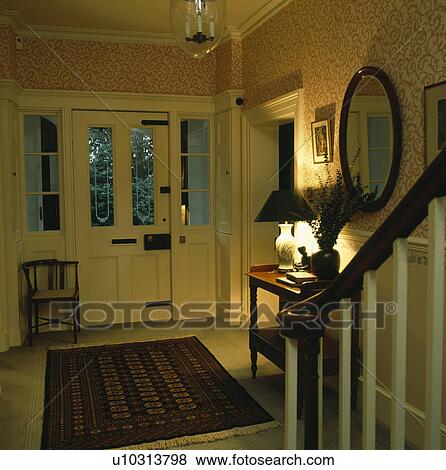 Stock Photo - Patterned wallpaper in hall with half-glazed front door and oriental rug on the floor. Fotosearch