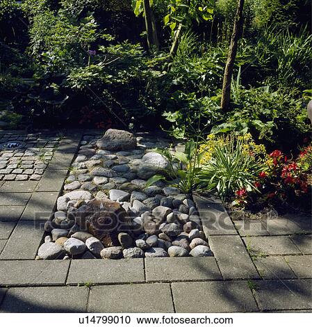 Stock Image - Pebble and stone paving in country garden in summer. Fotosearch