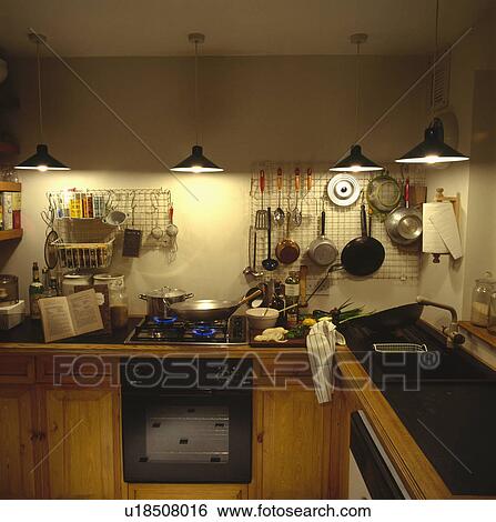 Pendant lighting and metal wall storage racks in small kitchen pans on lighted gas hob View Large Photo Image Stock Photograph - Pendant lighting and metal wall storage racks in small kitchen pans on lighted gas hob. Fotosearch