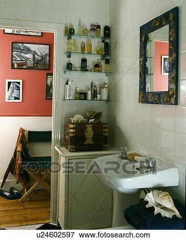 Perfume bottles on glass shelves in corner of small bathroom with door open to the landing View Large Photo Image Stock Photo - Perfume bottles on glass shelves in corner of small bathroom with door open to the landing. Fotosearch