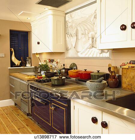 Stock Photo - Pestle and mortar on stainless steel worktop in modern kitchen with large black oven range below wall plaque. Fotosearch