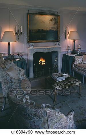 Stock Image - Picture above fireplace in traditional country living room with lighted lamps. Fotosearch