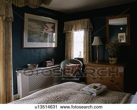 Picture above radiator with fretwork cover in black traditional bedroom with wicker chair beside chest-of-drawers View Large Photo Image Stock Image - Picture above radiator with fretwork cover in black traditional bedroom with wicker chair beside chest-of-drawers. Fotosearch