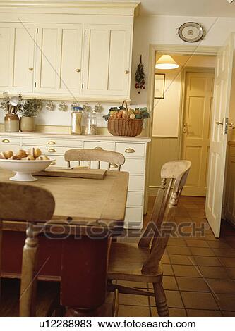 Pine table and chairs in cream country kitchen with terracotta tiled floor View Large Photo Image Stock Image - Pine table and chairs in cream country kitchen with terracotta tiled floor. Fotosearch