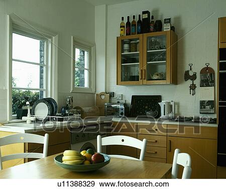 Pine table and white chairs in kitchen with wooden units View Large Photo Image Stock Photo - Pine table and white chairs in kitchen with wooden units. Fotosearch