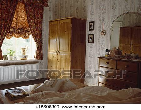 Stock Photo - Pine wardrobe in alcove of townhouse bedroom with wallpaper. Fotosearch