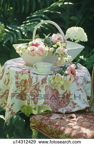 Stock Photo - Pink flowers and cloth on table in country garden in summer. Fotosearch