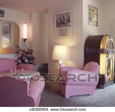 Picture - Pink leather three piece suite and jukebox in white room with grey carpet . Fotosearch