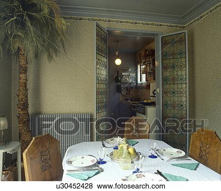 Place settings on table in small forties dining room with open stained glass double doors View Large Photo Image Stock Photo - Place settings on table in small forties dining room with open stained glass double doors. Fotosearch