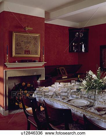 Place Settings On White Cloth On Table In Red Country Dining Room With Picture Above Fireplace Stock Photograph U12846336 Fotosearch