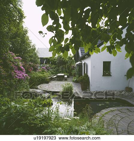 Stock Image - Pond and paving in town garden. Fotosearch