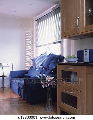 Stock Image - Practical dark blue upholstered sofa in front of window in living area of family kitchen.. Fotosearch