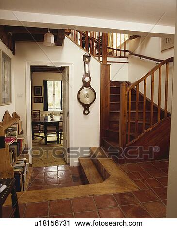 Stock Image - Quarry tiles in country hall with wooden staircase and barometer on the wall. Fotosearch