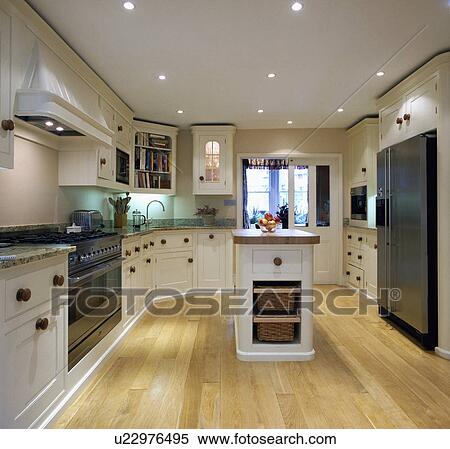 Recessed halogen lighting and wooden flooring in modern white kitchen with island unit View Large Photo Image Stock Photography - Recessed halogen lighting and wooden flooring in modern white kitchen with island unit. Fotosearch