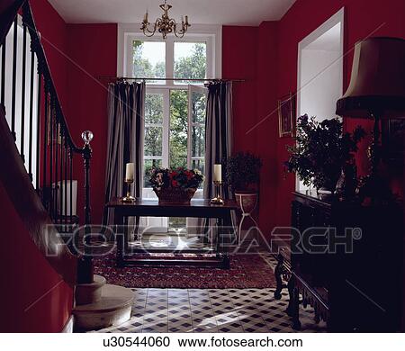 Stock Image - Red country hall with striped curtains at French doors. Fotosearch