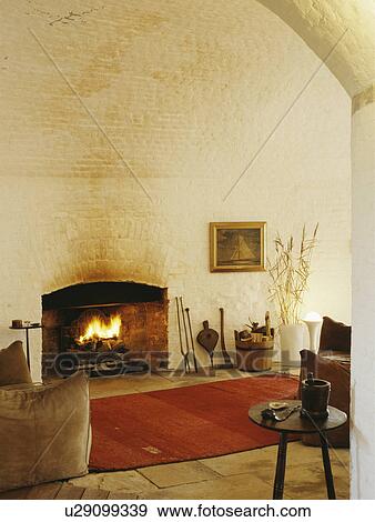 Stock Photo - Red rug in front of lighted fire in living room in converted Martello tower. Fotosearch