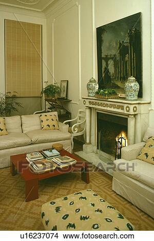 Picture - Red table and white sofa in traditional living room with picture above fireplace. Fotosearch