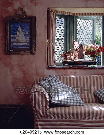 Stock Photography - Red+white striped sofa below window in cottage living room with pink marble-effect walls. Fotosearch