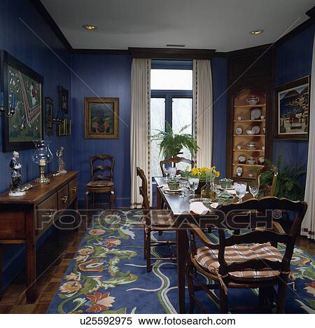 Stock Photography - Richly patterned blue carpet in blue dining room with antique furniture. Fotosearch