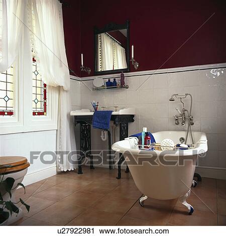 Rolltop bath in traditional black and white bathroom with terracotta tiled flooring and white tiled walls to dado height View Large Photo Image Stock Image - Rolltop bath in traditional black and white bathroom with terracotta tiled flooring and white tiled walls to dado height. Fotosearch