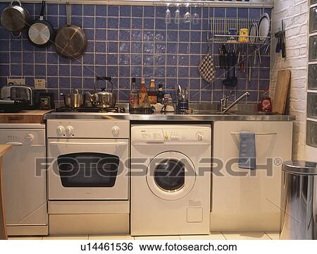 Row of white domestic appliances below blue wall tiles in economy style kitchen View Large Photo Image Stock Photograph - Row of white domestic appliances below blue wall tiles in economy style kitchen. Fotosearch